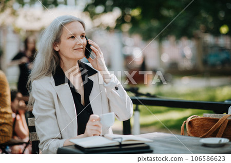 Portrait of beautiful female manager in middle age with gray hair making a phone call outdoors. 106586623