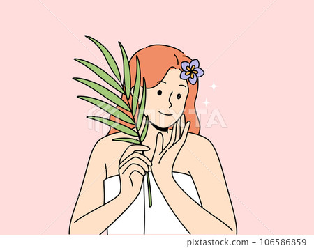 Woman with sprig of medicinal plant used for cosmetic purposes, stands in bath towel 106586859