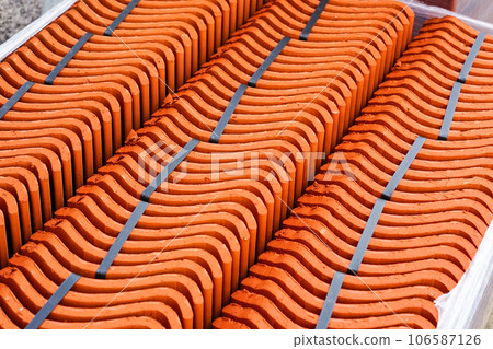 Packed in rows new red brown roof fired clay tiles, delivered to a restoration facility Packed in rows new red brown roof fired clay tiles, delivered to a restoration facility 106587126