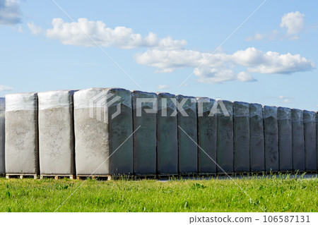 Peat extraction, many large bags of peat on the production area of a factory under a blue sky 106587131