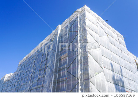 Insulation works of the facade of multistorey residential building, facade covered with safety net 106587169