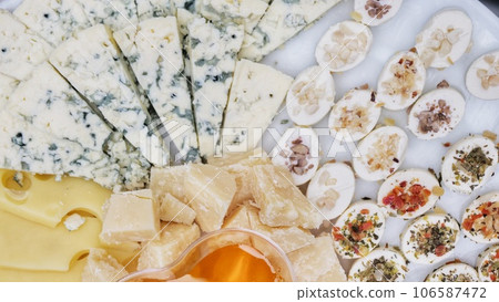plate of snacks with assorted cheese and honey dish. View from above. plate of snacks with assorted cheese and honey dish. View from above. 106587472