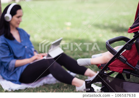 Small feet of infant baby dreaming in stroller near mother with earphones working online with mobile device in spring park active motherhood and career concept Small feet of infant baby dreaming in stroller near mother with earphones working online with mobile device in spring park active motherhood and career concept 106587638