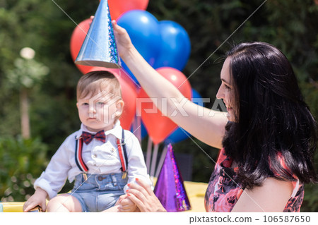 Mother and son first year with birthday festivities, scene is filled with balloons, party hats, and an array of delightful birthday decorations. Mother and son first year with birthday festivities, scene is filled with balloons, party hats, and an array of delightful birthday decorations. 106587650