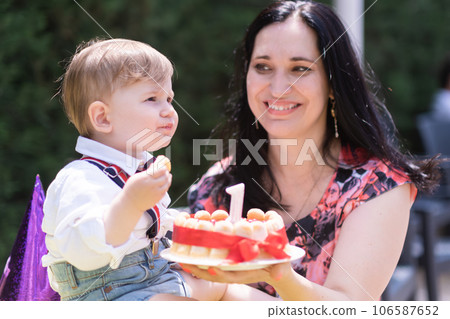 Family bond and celebration - 1 year old baby boy and his mother special day, delighting in a birthday cake candle. Family bond and celebration - 1 year old baby boy and his mother special day, delighting in a birthday cake candle. 106587652