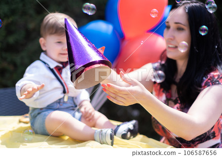 Playful bubble-catching at the birthday one-year-old baby joyfully festive backdrop of colorful balloons, celebrating their special day. Playful bubble-catching at the birthday one-year-old baby joyfully festive backdrop of colorful balloons, celebrating their special day. 106587656