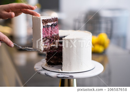 Woman taking cut piece of delicious sugar free cake covered with white mastic with spatula on blurred background finished homemade custom confectionery for event closeup Woman taking cut piece of delicious sugar free cake covered with white mastic with spatula on blurred background finished homemade custom confectionery for event closeup 106587658