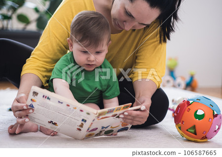 Loving mother enjoying educating little son sitting on floor near toys in nursery woman and chubby baby boy spending time together at home kids growth and development Loving mother enjoying educating little son sitting on floor near toys in nursery woman and chubby baby boy spending time together at home kids growth and development 106587665