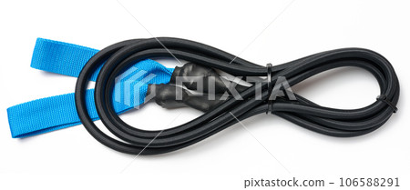 Black and blue rubber resistance tape for sports, folded and secured with a clip. Blue fabric handles. The background is white. Black and blue rubber resistance tape for sports, folded and secured with a clip. Blue fabric handles. The background is white. 106588291