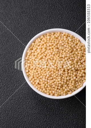 Raw ptitim pasta in a ceramic bowl on a dark concrete background Raw ptitim pasta in a ceramic bowl on a dark concrete background 106588313