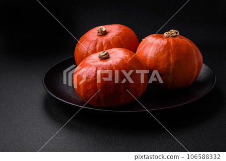 Beautiful fresh round pumpkins in orange color on a dark concrete background Beautiful fresh round pumpkins in orange color on a dark concrete background 106588332