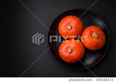 Beautiful fresh round pumpkins in orange color on a dark concrete background 106588333