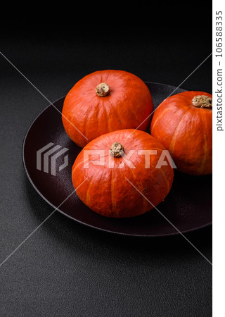 Beautiful fresh round pumpkins in orange color on a dark concrete background Beautiful fresh round pumpkins in orange color on a dark concrete background 106588335