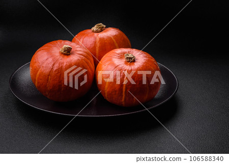 Beautiful fresh round pumpkins in orange color on a dark concrete background 106588340