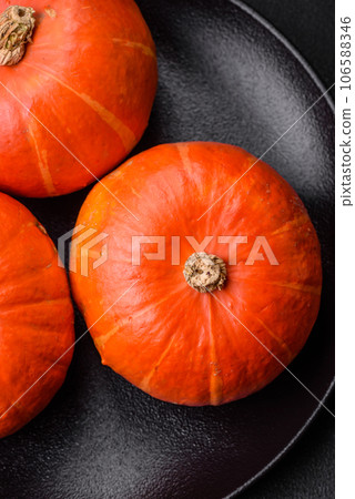Beautiful fresh round pumpkins in orange color on a dark concrete background 106588346