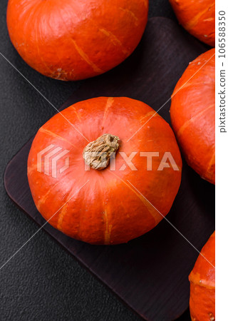 Beautiful fresh round pumpkins in orange color on a dark concrete background Beautiful fresh round pumpkins in orange color on a dark concrete background 106588350