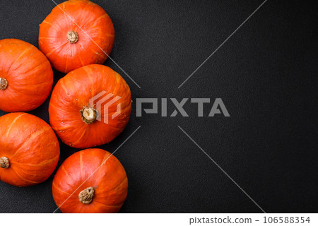 Beautiful fresh round pumpkins in orange color on a dark concrete background Beautiful fresh round pumpkins in orange color on a dark concrete background 106588354