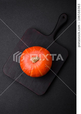 Beautiful fresh round pumpkins in orange color on a dark concrete background Beautiful fresh round pumpkins in orange color on a dark concrete background 106588363