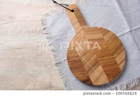 Empty round oak board and gray towel on a wooden table, top view 106588824