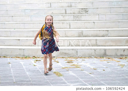 Joyful young pupil school girl with a yellow backpack, a smiling schoolgirl in her autumn morning journey to study 106592424