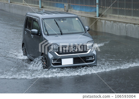 一輛汽車在被大雨淹沒的道路上行駛 一輛汽車在被大雨淹沒的道路上行駛 106593004