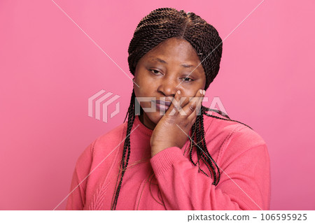 Emotional sick young adult having painful toothache while posing over pink background, needed medical health care in studio. Woman touching cheek suffering from terrible strong teeth pain. Emotional sick young adult having painful toothache while posing over pink background, needed medical health care in studio. Woman touching cheek suffering from terrible strong teeth pain. 106595925