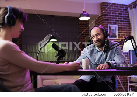 Happy show host interviewing woman during live stream, talking about fashion and style trends. Man talking with social media star, recording episode for online podcast channel 106595957