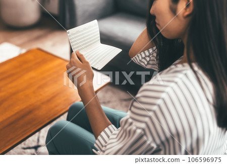 Young woman looking at bank passbook 106596975