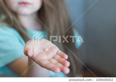 Little cute blonde girl child holding and showing her fallen milk front tooth in hands Little cute blonde girl child holding and showing her fallen milk front tooth in hands 106600082