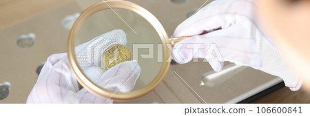 Woman numismatist examining coin with magnifier 106600841