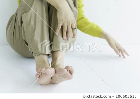 Feet of a young woman sitting on white background 106603613