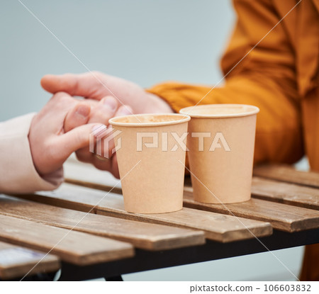 Close up hands man and woman drinking coffee or tea in disposable paper cup while spending time in outdoor cafe. Eco material. 106603832