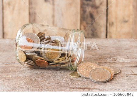 Glass jar with coins on wooden table 106603942