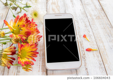 Smart phone and fresh flowers on wood table 106604043