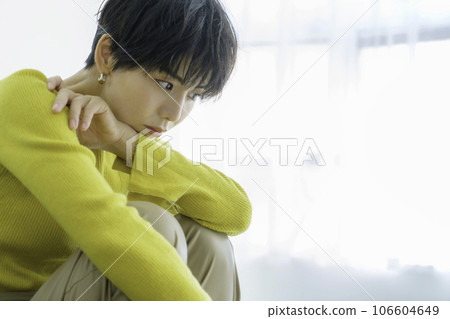 一位身穿黃色衣服的年輕女子坐在白色背景的綠色沙發上 106604649