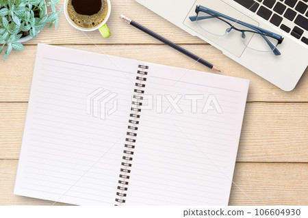 Office desk table with blank notebook, laptop computer, black pencil,glasses and cup of coffee. Office desk table with blank notebook, laptop computer, black pencil,glasses and cup of coffee. 106604930