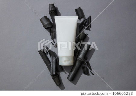 Empty label tube in white color placed on a pile of activated charcoal sticks. Activated bamboo charcoal help the body can excrete toxins out to purify and detoxify the body 106605258