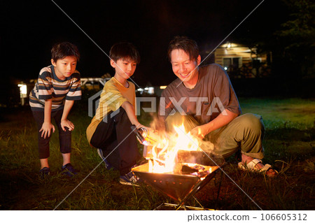 Children and adults enjoying a bonfire family camp image Children and adults enjoying a bonfire family camp image 106605312