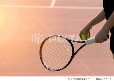 Tennis balls and rocket on court field in sunny day Tennis balls and rocket on court field in sunny day 106605385