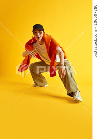 Young woman in stylish sportive clothes, hipster sitting and reading rap against yellow studio background Young woman in stylish sportive clothes, hipster sitting and reading rap against yellow studio background 106607280