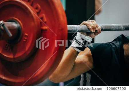 close-up red plates barbell and arm female powerlifter during squat close-up red plates barbell and arm female powerlifter during squat 106607300