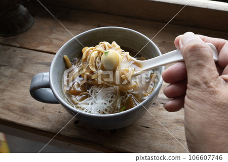 Someone eating fish maw in a bowl on wooden table. Someone eating fish maw in a bowl on wooden table. 106607746