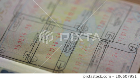 Close up part of foreign passport with foreign visas border stamps permits to enter countries concept of traveling around the world. Close up part of foreign passport with foreign visas border stamps permits to enter countries concept of traveling around the world. 106607951