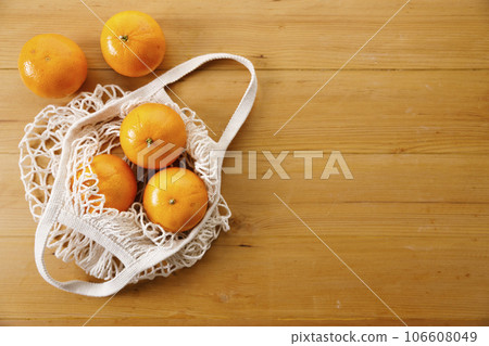 Oranges in Cotton mesh grocery bag on wooden background. Oranges in Cotton mesh grocery bag on wooden background. 106608049