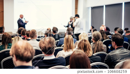 I have a question. Group of business people sitting at the chairs in conference hall. Businessman standing up asking a question. Conference and Presentation. Business and Entrepreneurship. 106608259