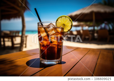 Refreshing Cola Soda Drink Closeup of Chilled Beverage with Lime Slice and Straw on Bar Counter, Against Blurry Tropical Beach Background. created with Generative AI Refreshing Cola Soda Drink Closeup of Chilled Beverage with Lime Slice and Straw on Bar Counter, Against Blurry Tropical Beach Background. created with Generative AI 106609025