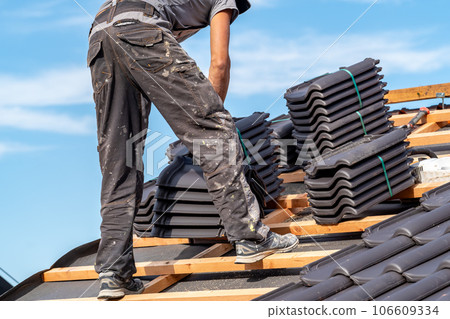 building a roof from ceramic tiles on a new family house, a craftsman on the construction site 106609334