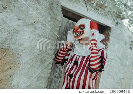 man is putting on a clown mask in front of a house man is putting on a clown mask in front of a house 106609436