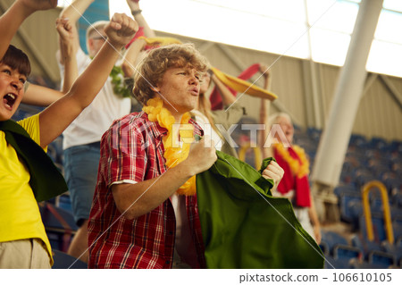 Tense game moment. Focus on concentrated and worried young man and boy, sport fan on stadium, cheering up favourite team during game 106610105