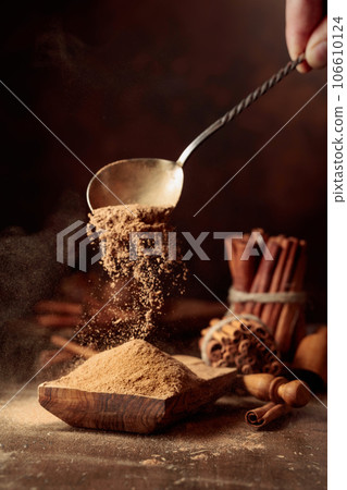 Cinnamon powder is poured into a wooden bowl. 106610124